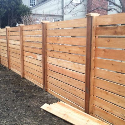 Photo of a custom horizontal pre-stained fence being installed by First Fence