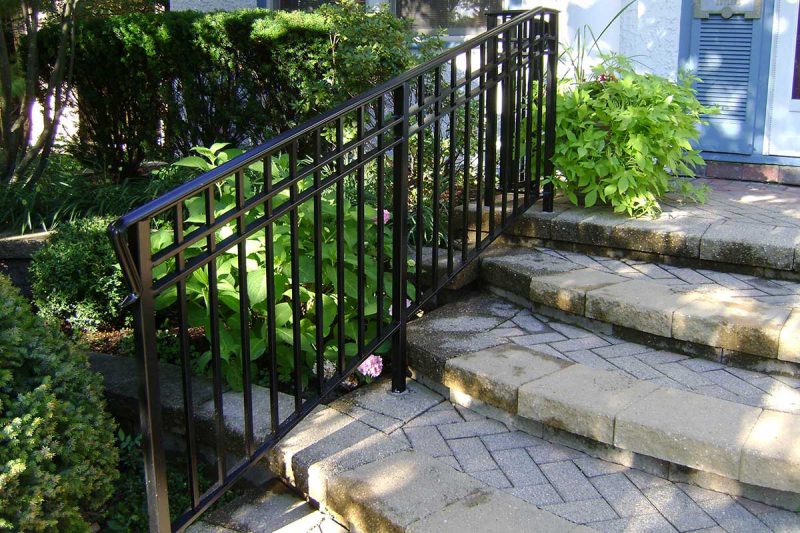 Photo of an iron railing down paver stairs - First Fence