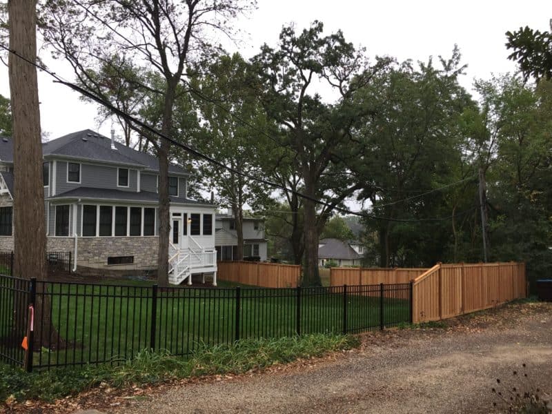 Photo of a wood fence connecting to an aluminum fence designed and installed by First Fence Company